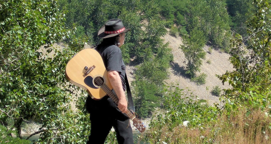 Dusty Woods and his acoustic guitar, walking down the road.